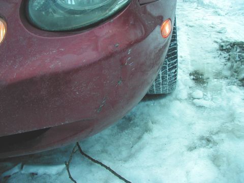 1997 Ford Taurus - The front corner of a red vehicle is shown in a snowy environment, with the tire and part of the headlight visible.