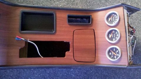 1982 Ford Bronco - This is a close-up shot of a custom dashboard console with a wood grain finish, featuring several gauges, a storage compartment, and an emp…
