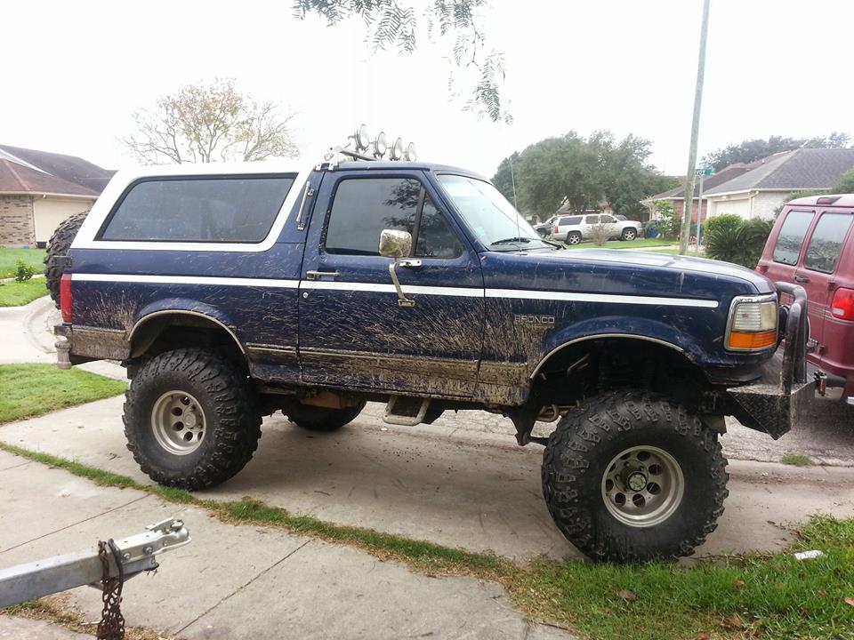 1994 Ford Bronco with white top and off-road tires covered in mud.
