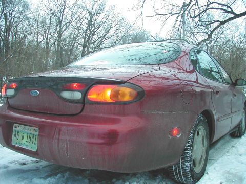 1997 Ford Taurus - Rear view of a red 1997 Ford Taurus parked in the snow.