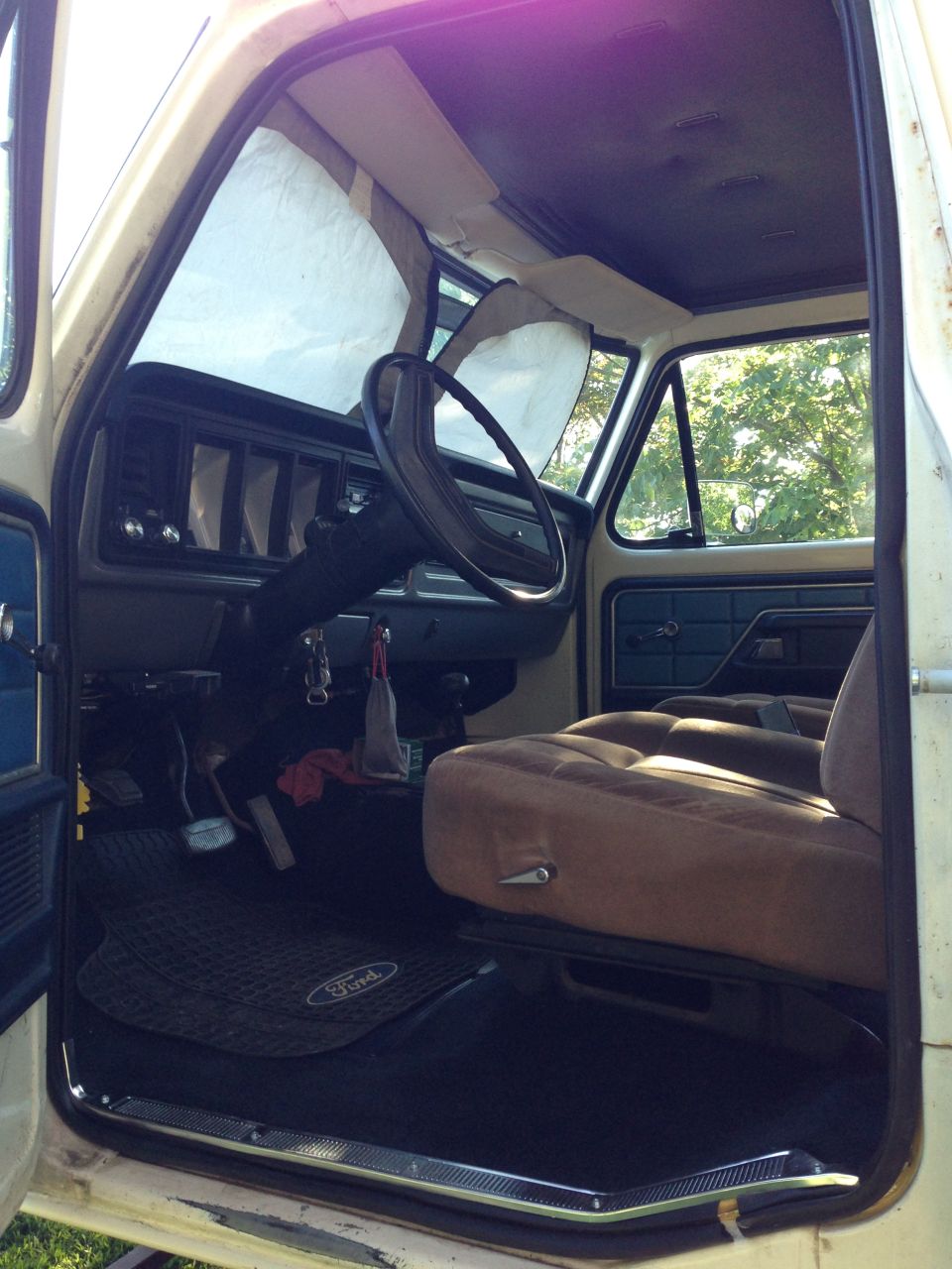 Interior of a vintage Ford truck or SUV, showing the driver's side, dashboard, and tan seat.