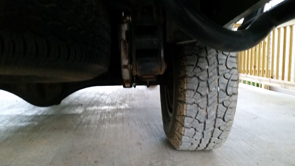 Rear suspension and tire of a vehicle, possibly a Nissan Frontier.