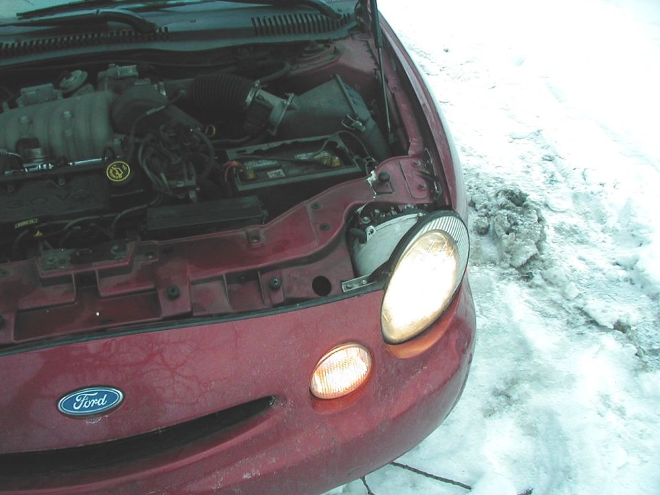 1997 Ford Taurus engine bay with hood open, showing engine components and front headlight