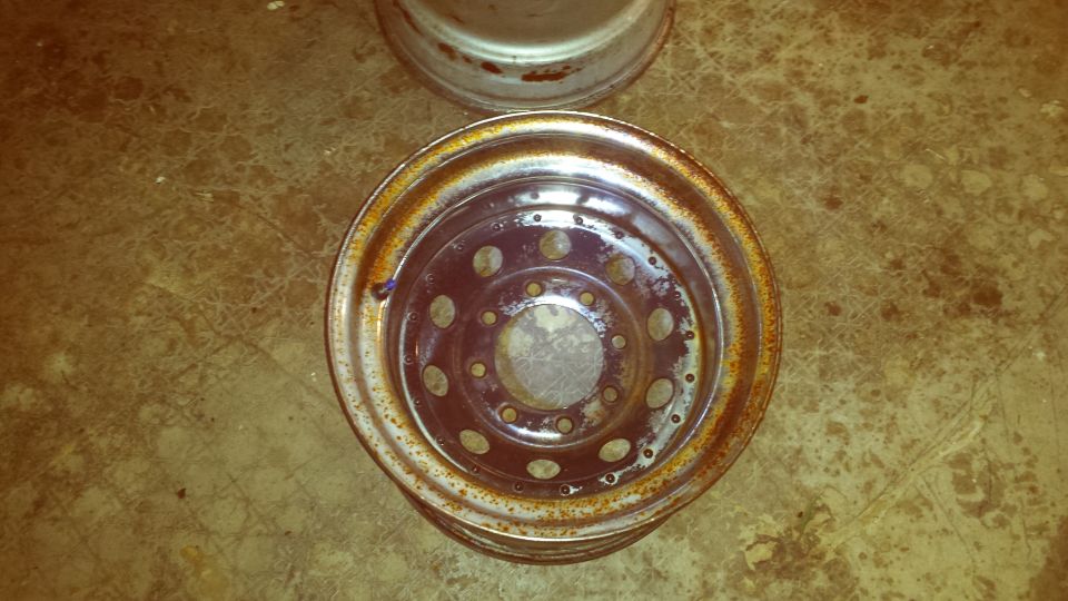 Two rusty metal wheel rims on a textured floor.