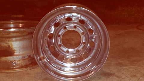 Two steel wheels, one chrome and one rusty, with the chrome wheel in focus.