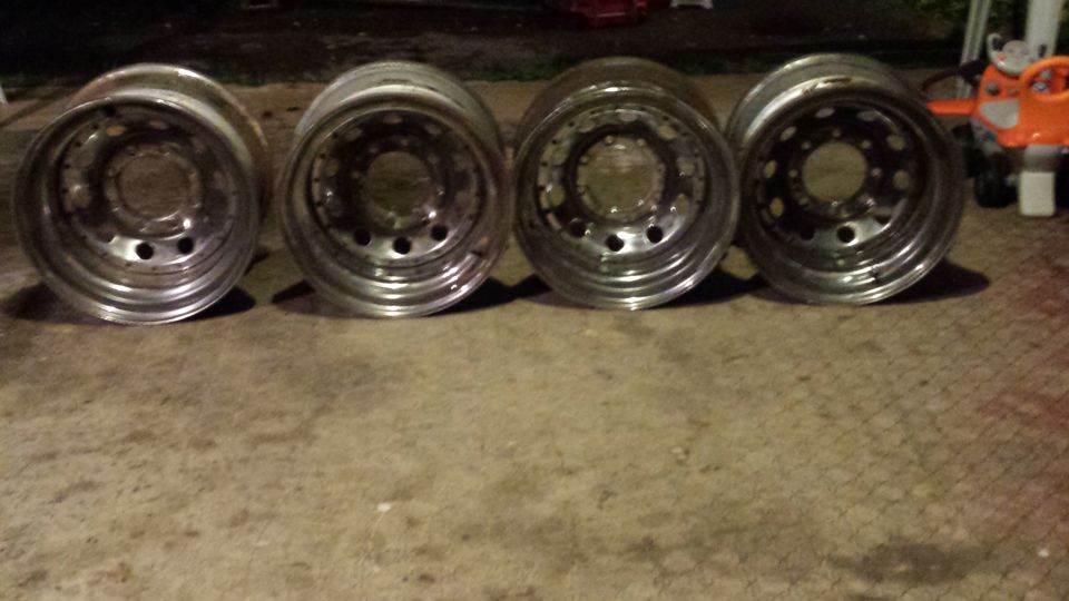 Four polished aluminum alloy wheels with multi-lug pattern and deep dish design.