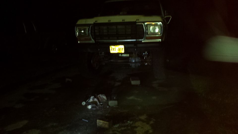 Lifted 1979 Ford Bronco front view at night, headlights on, yellow license plate "722 UTP"
