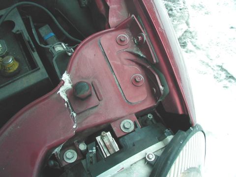 1997 Ford Taurus - Close-up view of a damaged car fender and headlight assembly, with a car battery visible in the background.