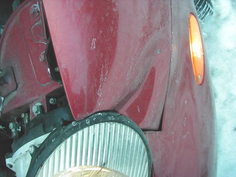 1997 Ford Taurus - Close-up of the front fender and wheel well of a red 1997 Ford Taurus.