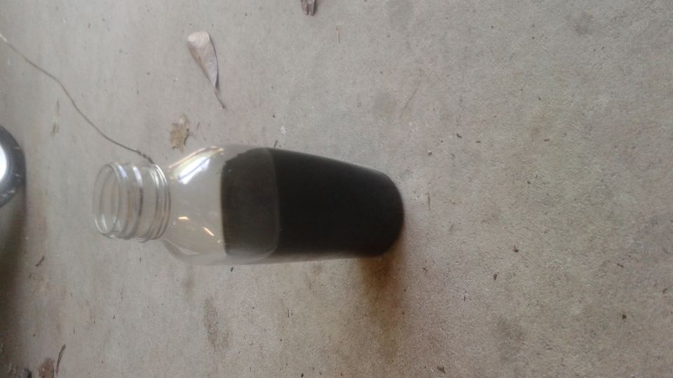 Glass bottle with dark liquid on concrete