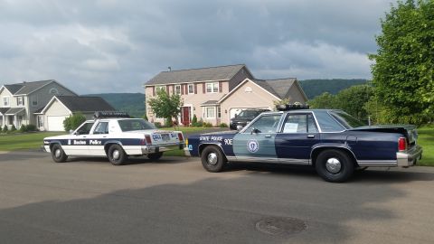 1991 Ford LTD Crown Victoria - Photograph of vintage police cars parked in a residential setting, not a technical document.