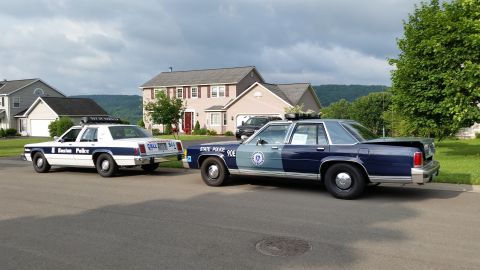 1991 Ford LTD Crown Victoria - Photograph of vintage police cars parked in a neighborhood, not a technical document.