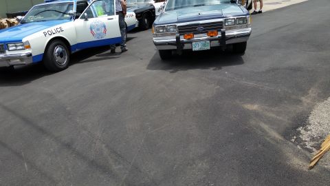 1991 Ford LTD Crown Victoria - Photograph of vintage police cars on pavement, not a technical document.