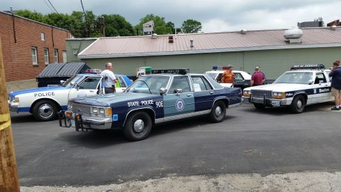1991 Ford LTD Crown Victoria - Photograph of vintage police cars in a parking lot, not a technical document.