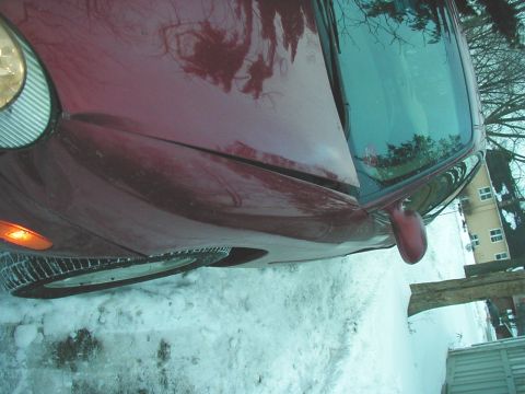 1997 Ford Taurus - A red 1997 Ford Taurus sits in the snow, showing its front 3/4 angle.