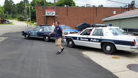 1991 Ford LTD Crown Victoria - Photograph of vintage police cars in a lot, not a technical document.
