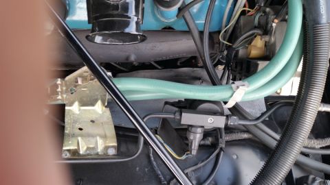 1991 Ford LTD Crown Victoria - Close-up photograph of engine bay plumbing with a green hose and vacuum fitting, not a technical document.