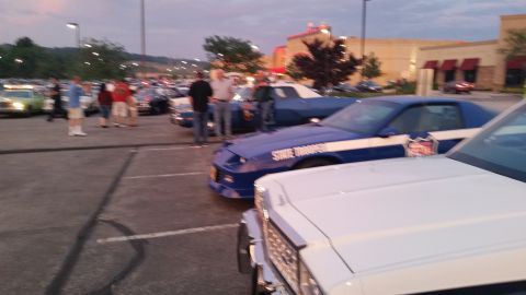 1991 Ford LTD Crown Victoria - Photograph of police and classic cars at a dusk car show, not a technical document.