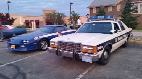 1991 Ford LTD Crown Victoria - Photograph of a State Trooper Camaro and police sedan at a car show, not a technical document.