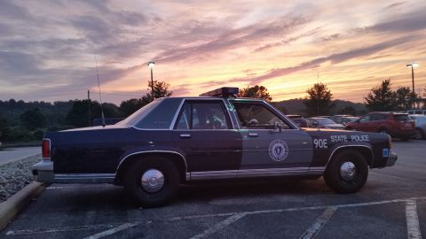 1991 Ford LTD Crown Victoria - Photograph of a State Police sedan cruiser at sunset, side profile, not a technical document.