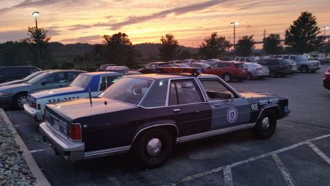 1991 Ford LTD Crown Victoria - Photograph of a State Police sedan cruiser parked among other cars at dusk, not a technical document.