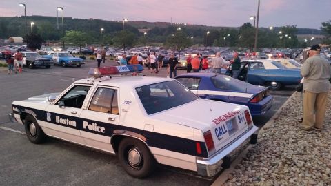 1991 Ford LTD Crown Victoria - Photograph of a Boston Police sedan cruiser at a busy car show at dusk, not a technical document.