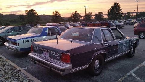 1991 Ford LTD Crown Victoria - Photograph of a State Police sedan and a vintage cruiser parked at sunset, not a technical document.