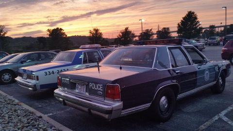 1991 Ford LTD Crown Victoria - Photo of vintage Ford and Chevrolet police cars parked at dusk, not a technical document.