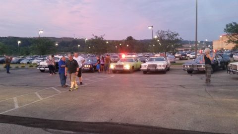 1991 Ford LTD Crown Victoria - Photo of a car-meet parking lot with people and vintage police cars, not a technical document.