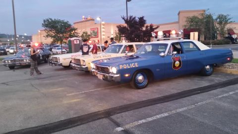 1991 Ford LTD Crown Victoria - Photo of a row of vintage police cars outside a restaurant at dusk, not a technical document.