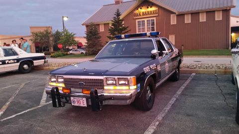1991 Ford LTD Crown Victoria - Photo of a vintage State Police Ford patrol car outside a restaurant, not a technical document.