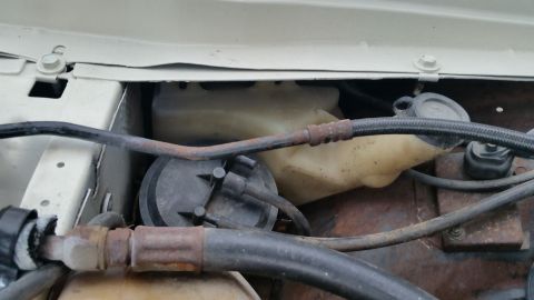 1991 Ford LTD Crown Victoria - Photo of an underhood washer-fluid reservoir and rusty hoses, not a technical document.