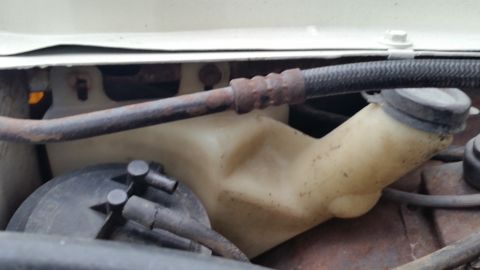 1991 Ford LTD Crown Victoria - Photo of a plastic washer-fluid reservoir and corroded lines under the hood, not a technical document.