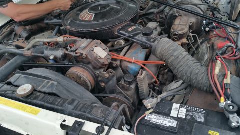 1991 Ford LTD Crown Victoria - Photo of a dusty vintage V8 engine bay with battery and plug wires, not a technical document.