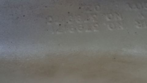 1991 Ford LTD Crown Victoria - Photo of embossed part numbers molded into a plastic reservoir, not a classifiable document.