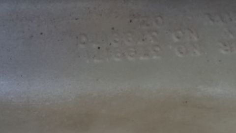 1991 Ford LTD Crown Victoria - Photo of embossed part numbers molded into a plastic reservoir, not a classifiable document.