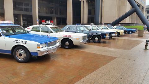 1991 Ford LTD Crown Victoria - Photo of a lineup of vintage police cars on a brick plaza, not a technical document.
