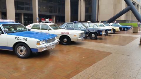 1991 Ford LTD Crown Victoria - Photo of vintage police cars lined up on a plaza, not a technical document.