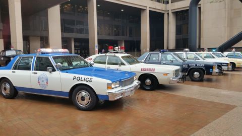 1991 Ford LTD Crown Victoria - Photo of a vintage Police Caprice and a lineup of patrol cars on a plaza, not a technical document.