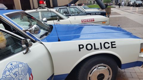 1991 Ford LTD Crown Victoria - Photo of vintage Police and Sheriff patrol cars on a plaza, not a technical document.