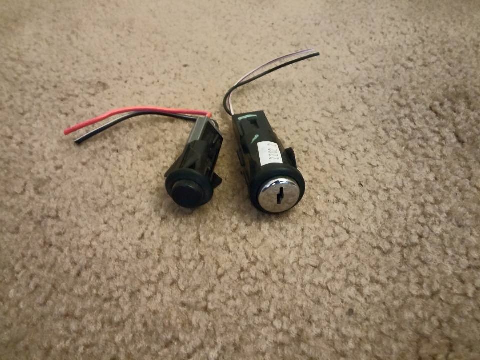 Two ignition lock cylinders with pigtail wiring on carpet