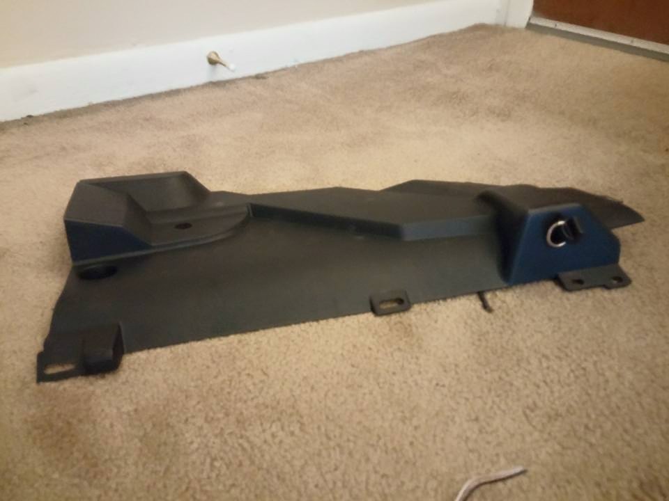 Black car floor mat on tan carpet