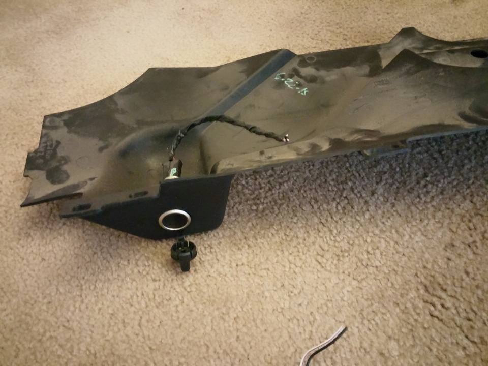 Close-up of a dark-colored car part with a metal clip attached