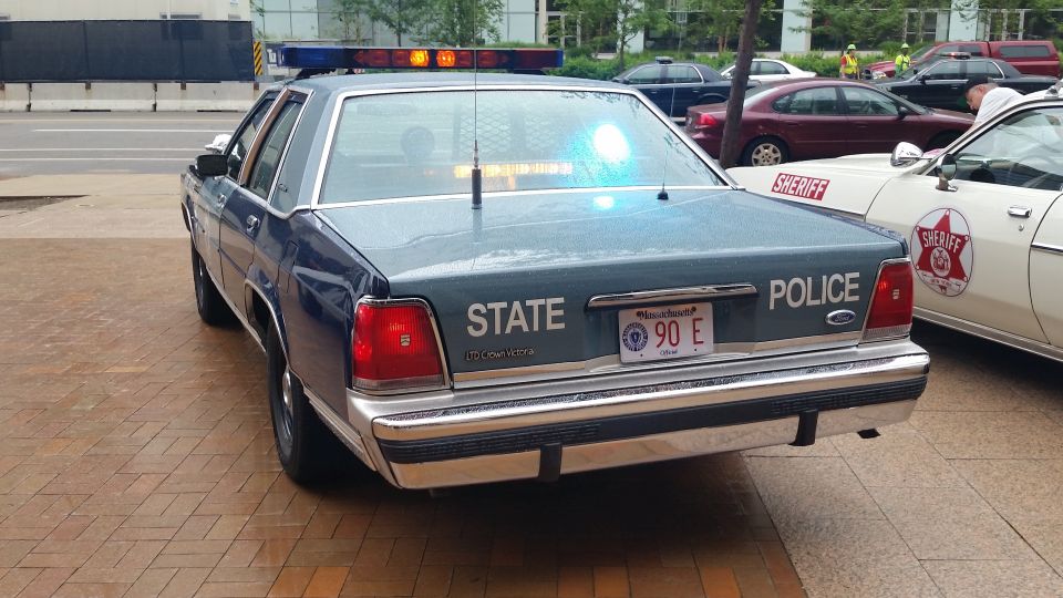 Rear of blue Massachusetts State Police Ford coupe with light bar