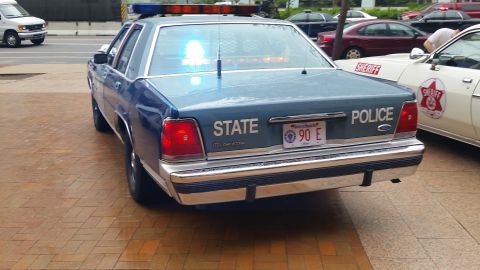 1991 Ford LTD Crown Victoria - Photograph of the rear of a blue State Police Ford sedan at a car show, not a technical document.