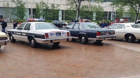 1991 Ford LTD Crown Victoria - Photograph of a Boston Police cruiser and other police cars at an outdoor display, not a technical document.