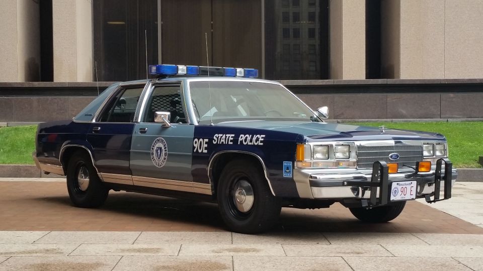 Blue Massachusetts State Police Ford cruiser, front three-quarter view