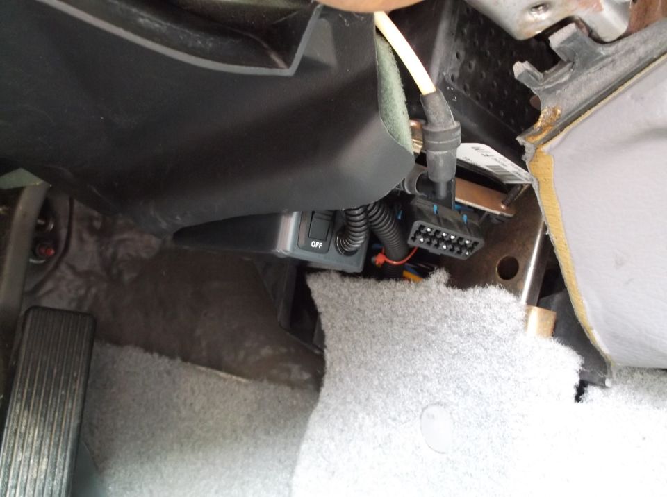 Close-up of an aftermarket switch and connector under a car dashboard.