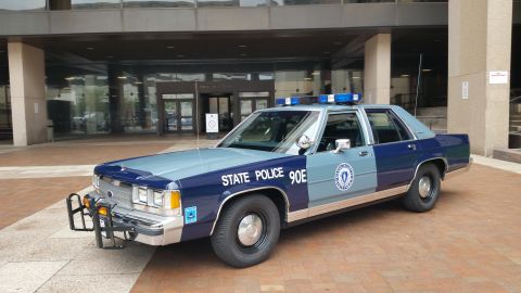 1991 Ford LTD Crown Victoria - Photo of a blue Massachusetts State Police Ford Crown Victoria cruiser, unit 90E, parked in front of a courthouse.