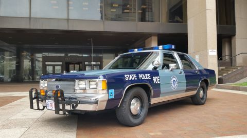 1991 Ford LTD Crown Victoria - Photo of a Massachusetts State Police Ford Crown Victoria cruiser, unit 90E, parked at a building entrance.